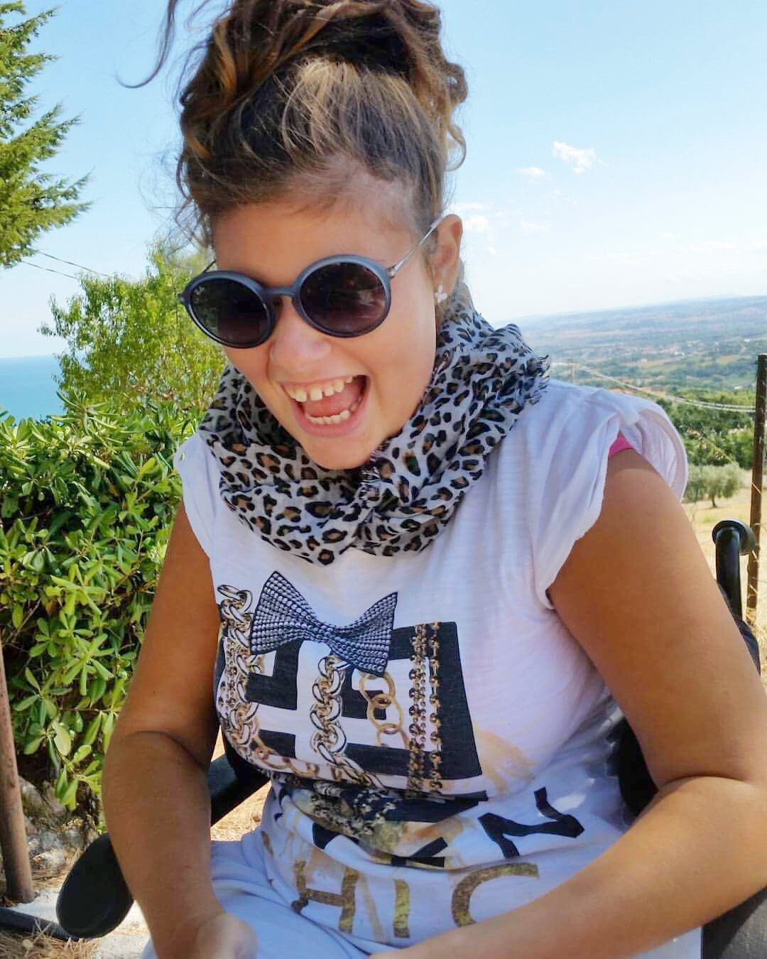 Asja sorridente in sedia a rotelle con occhiali scuri