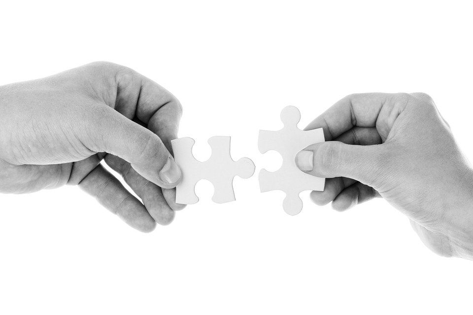 Due mani uniscono altrettanti pezzi di un puzzle