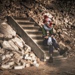 clown seduto su scale tra le macerie