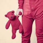 il corpo di un adulto con pigiamone e orso viola