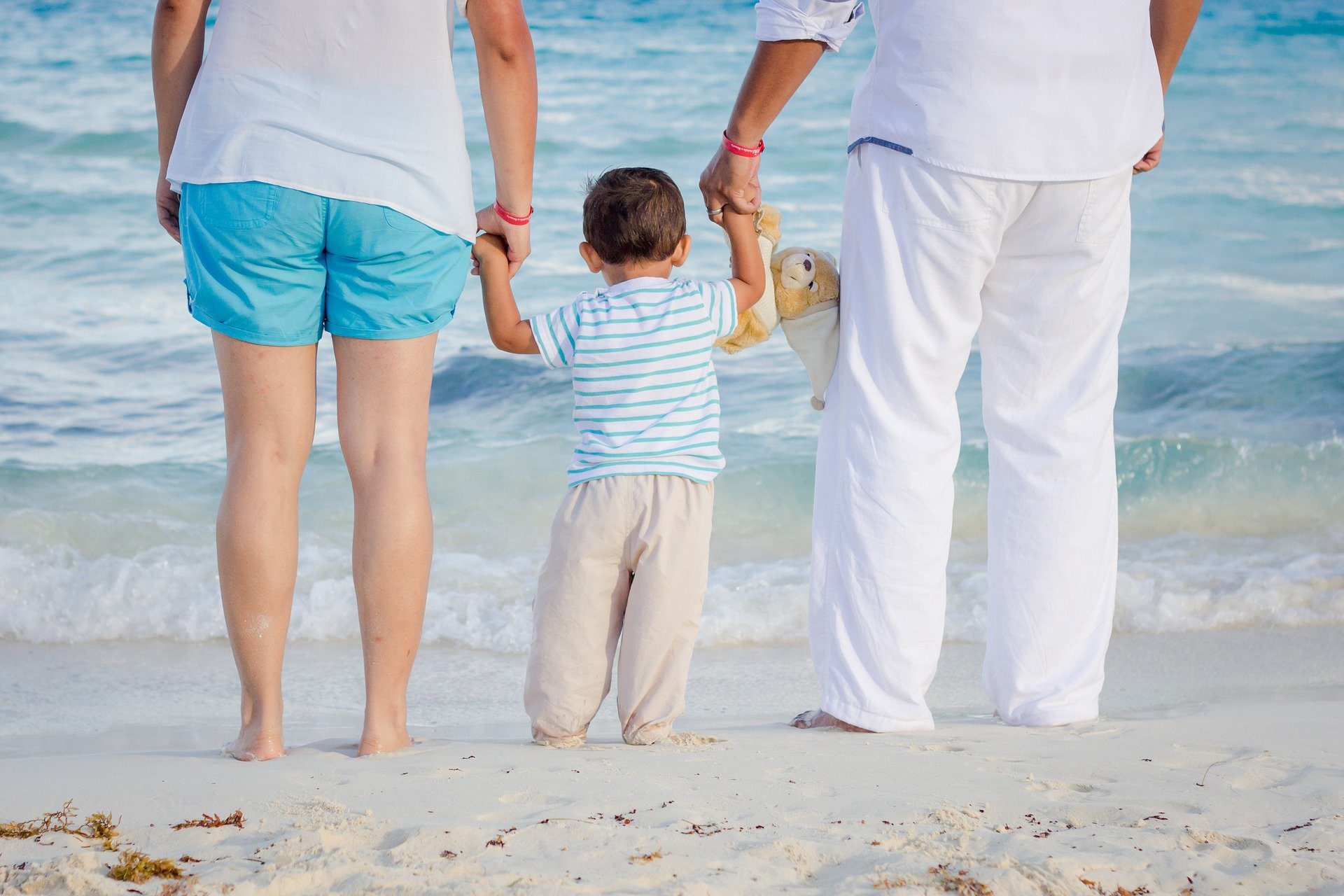 una famiglia per mano di spalle camminano verso il mare