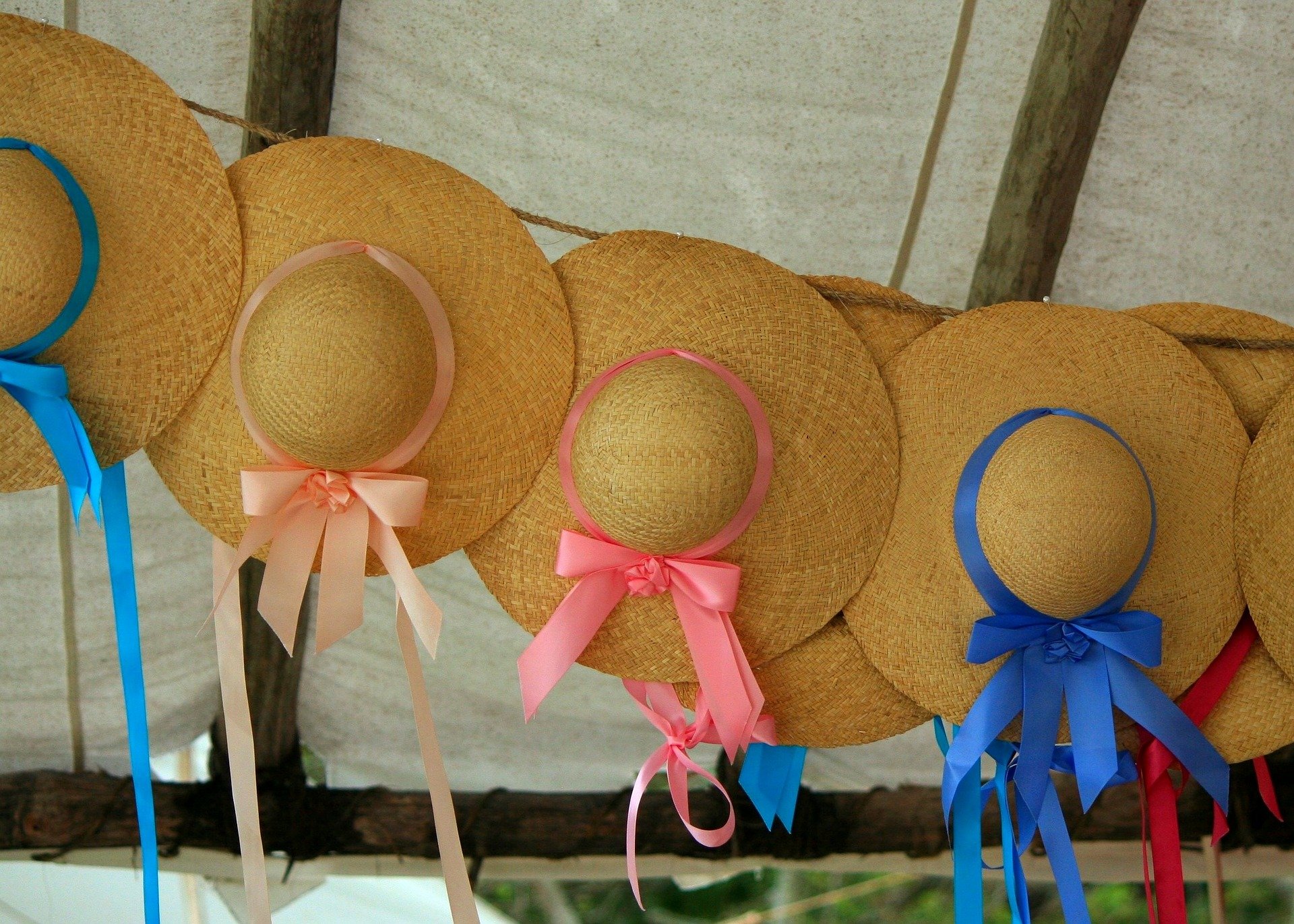più cappelli femminili di paglia con fiocchi blu e rosa appesi