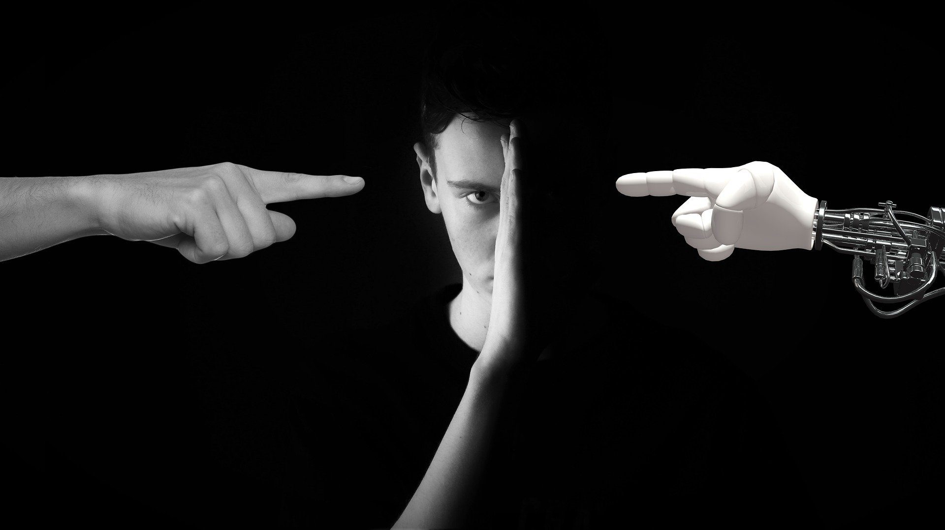 il volto di un ragazzo diviso a metà dove a sinistra una mano ne indica il viso e a destra un braccio meccanico ugualmente indica il viso ma oscurato