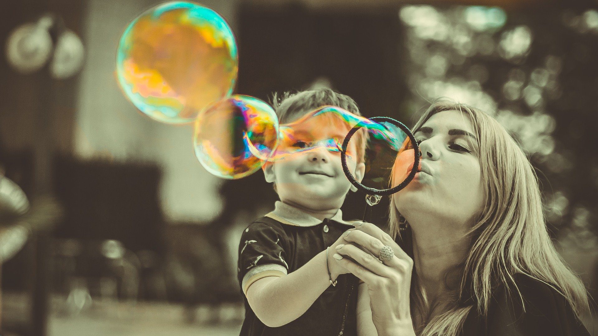 mamma con in braccio il figlio che fanno le bolle