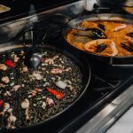 tre teglie di paella diverse su fornelli da ristorante
