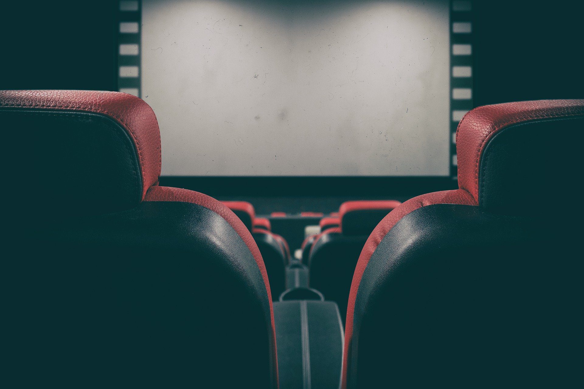 poltrone rosse di un cinema davanti allo schermo
