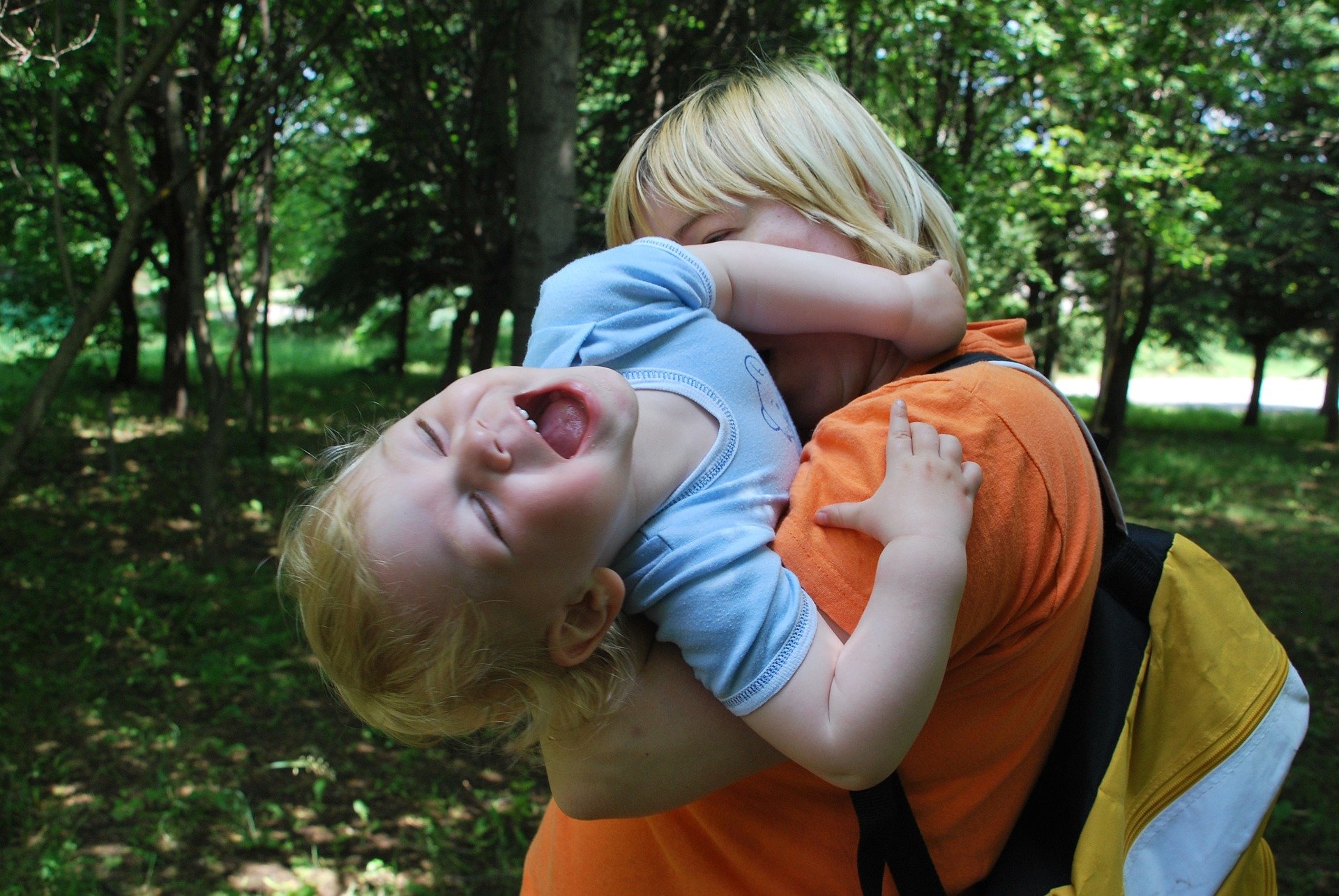 un bambino in braccio alla mamma che si divincola ridendo al solletico