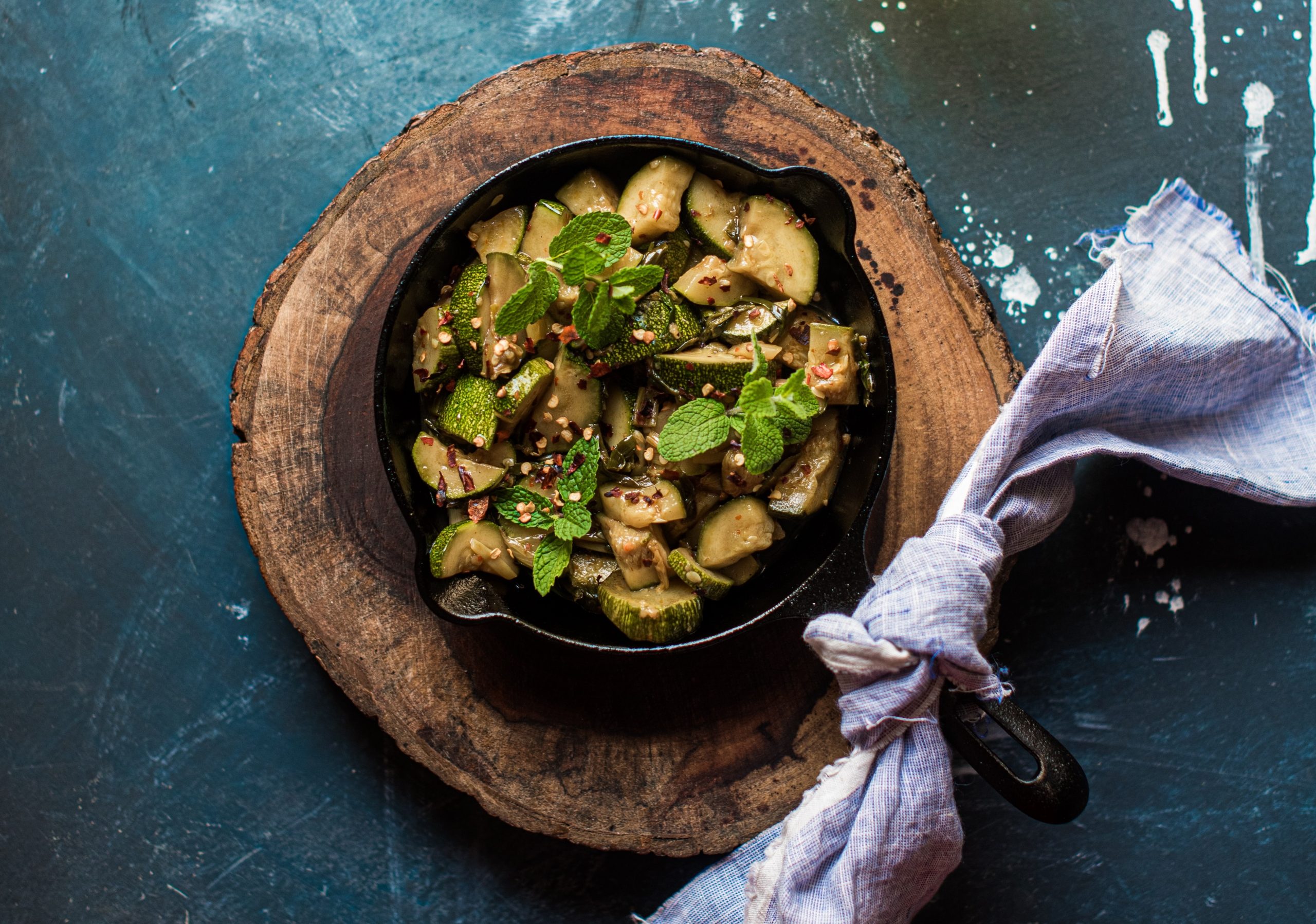 tagliere con sopra una pentola di zucchine marinate cotte