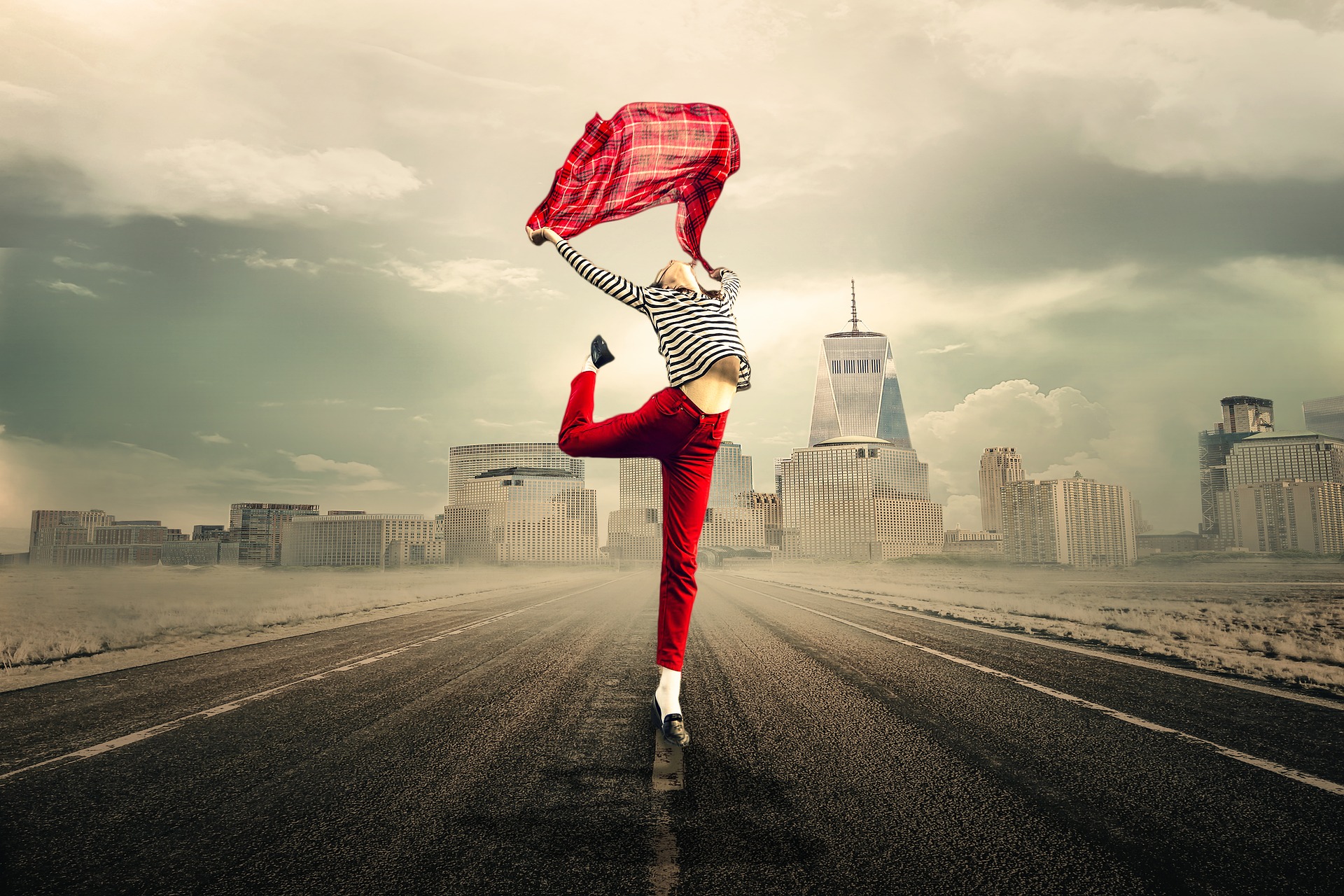 donna che corre e salta libera, con pantaloni e foulard al vento rossi, e sullo sfondo una città